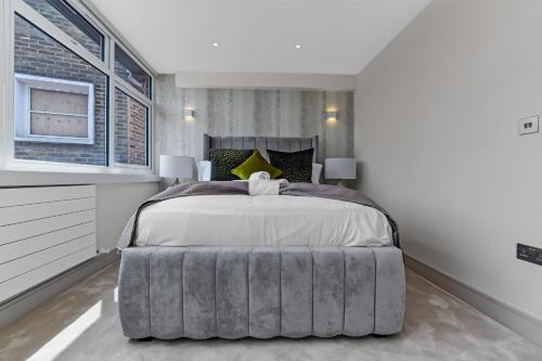 a bedroom with a large bed with a gray ottoman at 1 Bedroom stylish apartment in Webley park in London