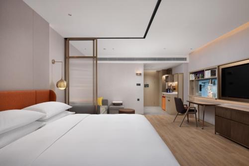 a hotel room with a large bed and a desk at Home2 Suites By Hilton Hotel Guangzhou Baiyun International Airport Branch - Free Shuttle Bus to Guangzhou Baiyun International Airport & Free Deliver Service to Canton Fair Complex During Canton Fair Period in Huadu