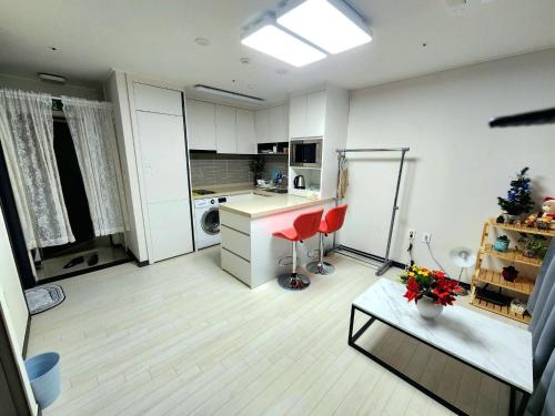 a kitchen with white cabinets and a table and red chairs at Apartment near Ilsan Dongkuk University Hospital in Goyang