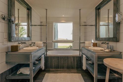 a bathroom with two sinks and a bath tub at Rosewood Kauri Cliffs in Matauri Bay