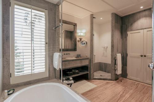 a bathroom with a tub and a shower and a sink at Rosewood Kauri Cliffs in Matauri Bay