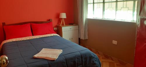- une chambre avec un lit bleu avec des oreillers rouges et une fenêtre dans l'établissement Departamento Familiar Pimentel - Ica, à Ica