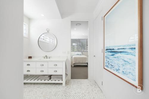 La salle de bains blanche est pourvue d'un lavabo et d'un miroir. dans l'établissement Lucy - Noosa - Noosaville, à Noosaville