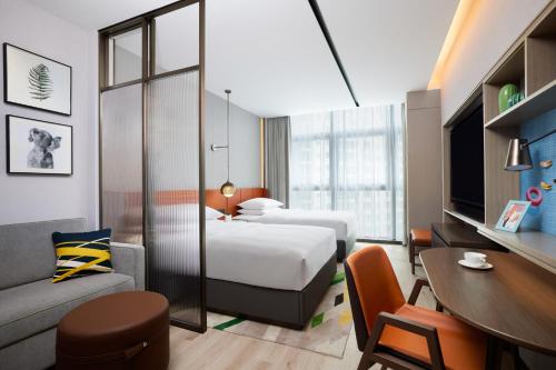 Home2 Suites by Hilton Guangzhou Baiyun Airport West في هوادو: غرفة فندقية بسريرين وطاولة