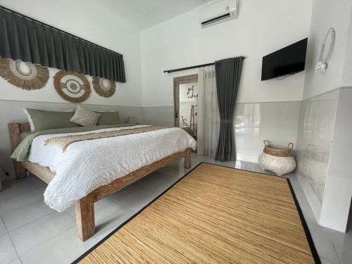 a bedroom with a bed and a television and a rug at Pennylane Villa in Seminyak