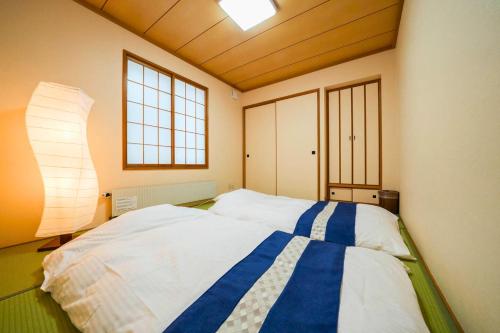 a bedroom with a large bed and a lamp at Canal Villa Otaru in Otaru