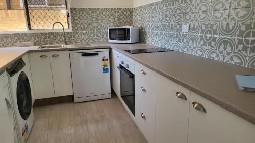 a kitchen with a microwave and a stove top oven at Husky 19 Beautifully Appointed Apartments - GREAT LOCATION - in the heart of Husky in Huskisson