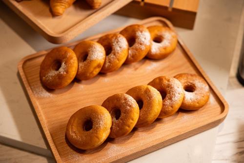 a group of donuts sitting on a wooden tray at Home2 Suites By Hilton Hotel Guangzhou Baiyun International Airport Branch - Free Shuttle Bus to Guangzhou Baiyun International Airport & Free Deliver Service to Canton Fair Complex During Canton Fair Period in Huadu