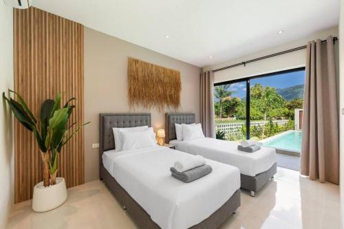 two beds in a bedroom with a pool at Jungle Retreat: Sereniwoods Villa Private Pool 3br in Koh Samui 
