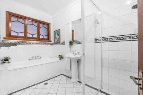 een witte badkamer met een wastafel en een douche bij Rosebay water front 4 bd home in Brisbane