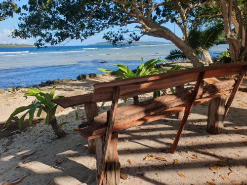 VitouaraにあるEco Dive Vanuatu Bungalows & Backpackersの海辺の浜辺に座る木製ベンチ