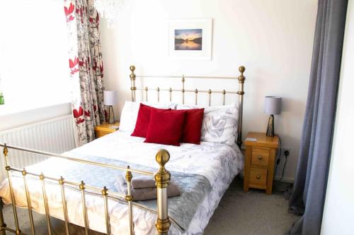 Un dormitorio con una cama con almohadas rojas. en Botany Bay House with Hot Tub, close to Beach, en Kent