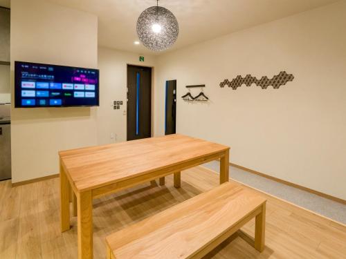 a table and bench in a room with a tv at Rakuten STAY Nikko Hoden in Nikko
