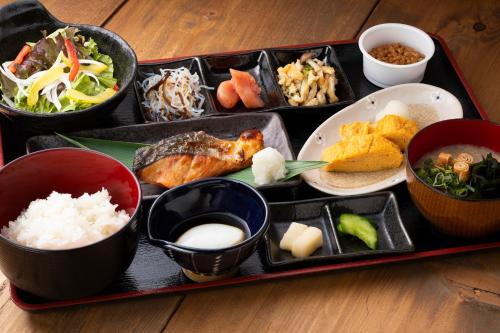 福岡市にあるホテルマイステイズ福岡天神のテーブルの上に様々な種類の食料を詰めたトレイ