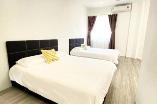 two beds in a bedroom with white sheets and yellow pillows at Grace Homestay Tawau in Tawau