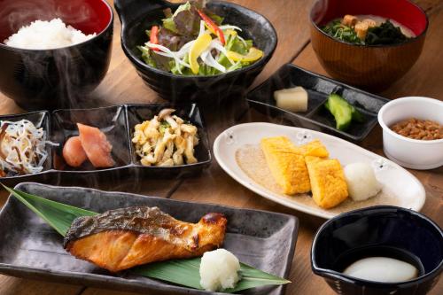 a table topped with plates of food and bowls of food at HOTEL MYSTAYS Fukuoka Tenjin in Fukuoka