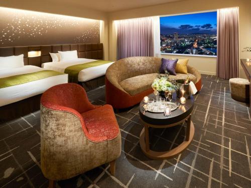 a hotel room with two beds and a table and chairs at Rihga Royal Hotel Kokura Fukuoka in Kitakyushu
