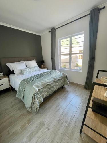 ein Schlafzimmer mit einem Bett und einem großen Fenster in der Unterkunft Claptons Cottage 12 in Jeffreys Bay