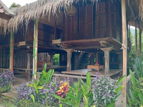 a wooden house with a thatched roof and some flowers at Sekumpul Bali Hidden Space in Singaraja