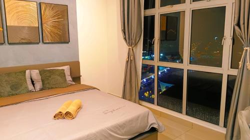 a bedroom with a bed with a window and two towels at Kulai d'putra suites beside ioiMall near Airport and JPO in Kulai