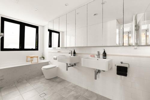 雪梨的住宿－4 bedrooms family home in Bronte，白色的浴室设有2个盥洗盆和1个卫生间。