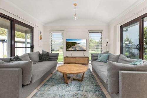 Una sala de estar con dos sofás y una mesa de café. en Coorie Nook by Experience Jervis Bay, en Vincentia