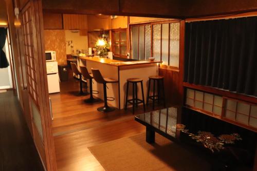 eine Küche mit einer Theke und eine Bar mit Hockern in der Unterkunft 【一棟貸し切り】海辺の静かな古民家宿『１』 in Tateishi