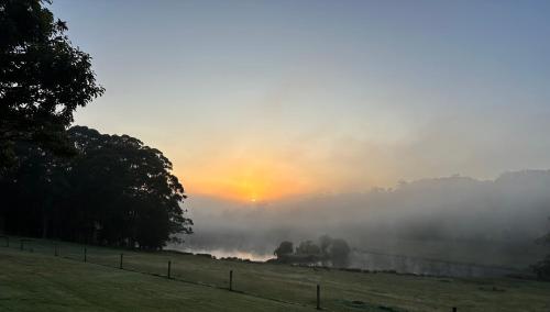un campo de niebla con una puesta de sol en el fondo en Springwood Cottage, en Denmark