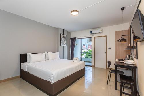 a bedroom with a white bed and a desk and a window at Infinite Hotel-Ratchada in Bangkok