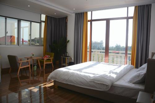 a bedroom with a bed and a table and a large window at Banyan Bay Homestay, Meizhou Island in Meizhou