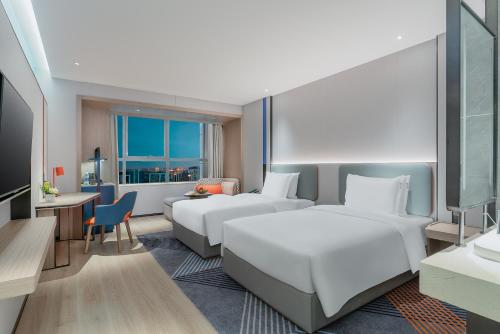 een hotelkamer met 2 bedden en een bureau bij Holiday Inn Express Changsha Development Zone, an IHG Hotel in Xingsha