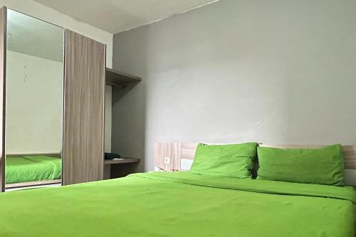 a bedroom with a green bed and a mirror at Barata Home in Tangerang