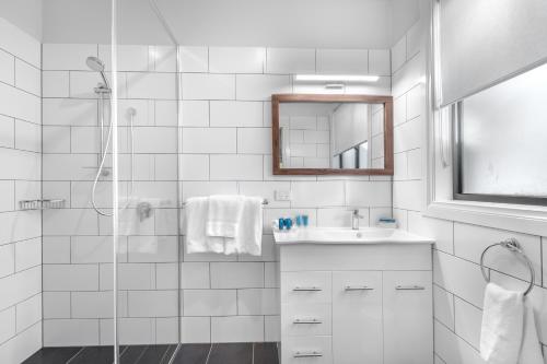 a white bathroom with a shower and a sink at Club Wyndham Pokolbin Hill in Pokolbin