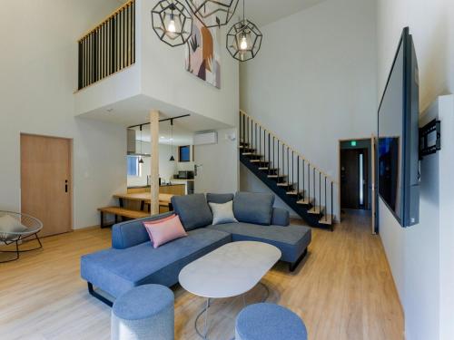a living room with a blue couch and a table at Rakuten STAY VILLA Fujikawaguchiko Forest in Fujikawaguchiko