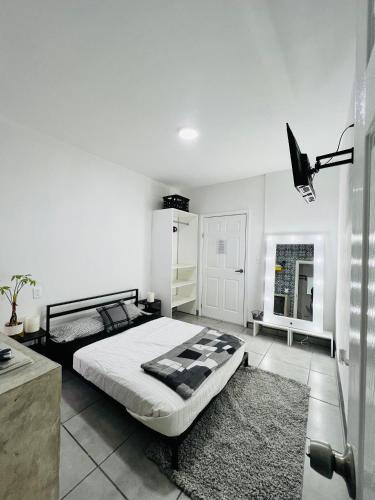 a white bedroom with a bed and a window at CASA AMBAR in Tijuana