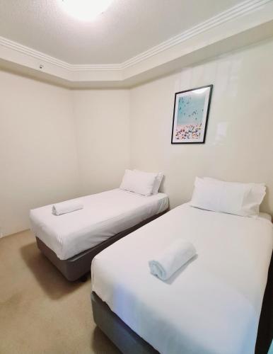 two beds in a room with white walls at Crystal Bay On The Broadwater in Gold Coast