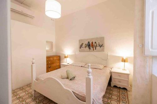 a white bedroom with a bed and a painting on the wall at Harbour view in Senglea