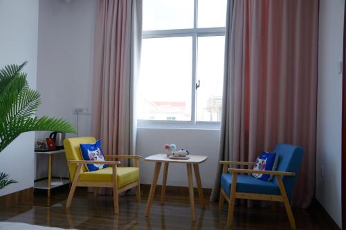 een kamer met 2 stoelen, een tafel en een raam bij Banyan Bay Homestay, Meizhou Island in Meizhou