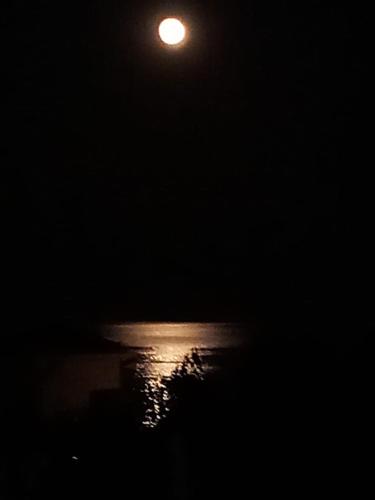 a full moon over the ocean at night at zikos house in Monemvasia