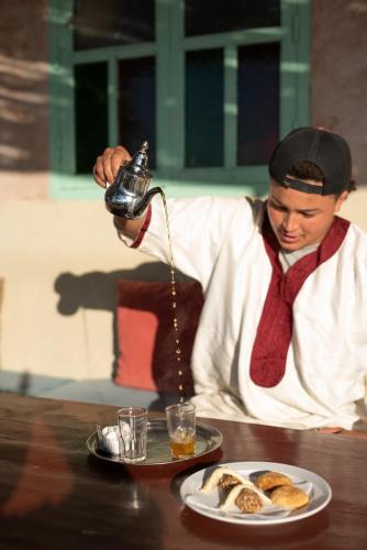 a man is pouring food into a plate of food at Dar Afoulky Maison D'hotes in Sidi Kaouki