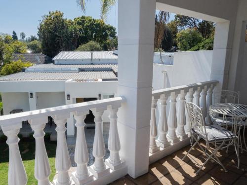 Una barandilla blanca en un balcón con una silla en Kelkiewyn Waterkloof Guesthouse, en Pretoria