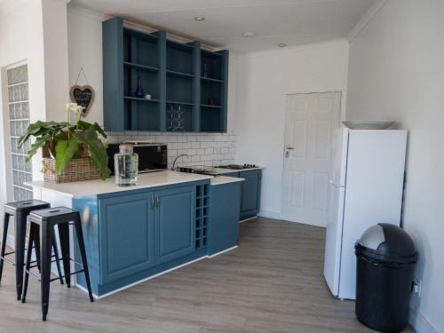 a kitchen with blue cabinets and a white refrigerator at Kelkiewyn Waterkloof Guesthouse in Pretoria