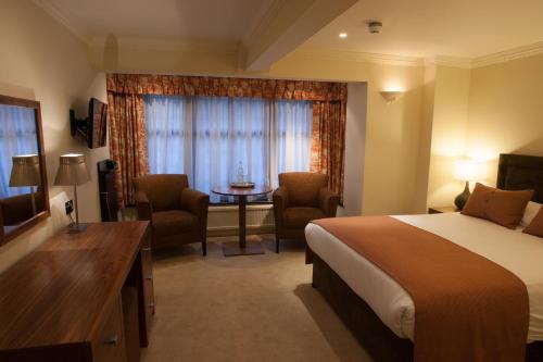 a hotel room with a bed and a table and chairs at Stirrups Hotel in Bracknell