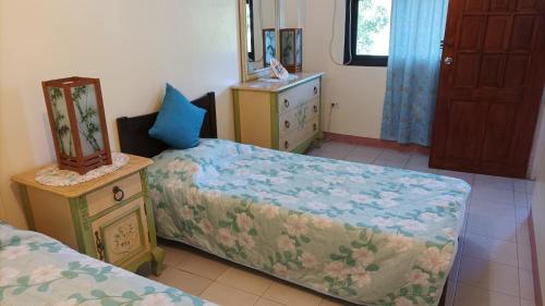 1 dormitorio con 2 camas, tocador y espejo en Hundred Islands Guest House, en Alaminos