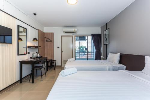 a hotel room with two beds and a desk at CK2 Hotel SHA EXTRA PLUS in Bangkok