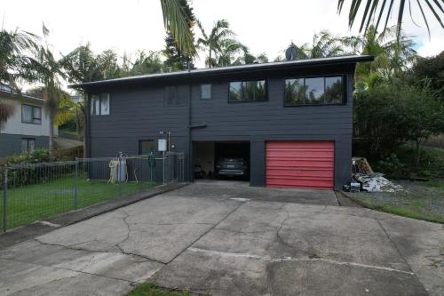 una casa con un garaje con una puerta de garaje roja en Huriana Place, en Kaitaia