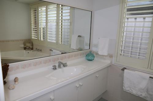 a white bathroom with a sink and a mirror at Villa Del Mar in Myola
