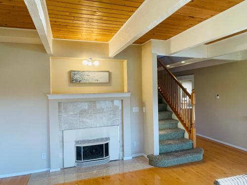 a living room with a fireplace and a staircase at Lake Tapps Dock House on the Bankers Island in Dieringer