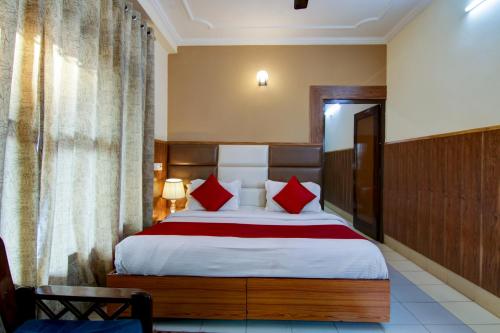 a bedroom with a large bed with red pillows at Hotel Varuni- On Mall Road, Mcleod Ganj, Dharamshala in Dharamshala