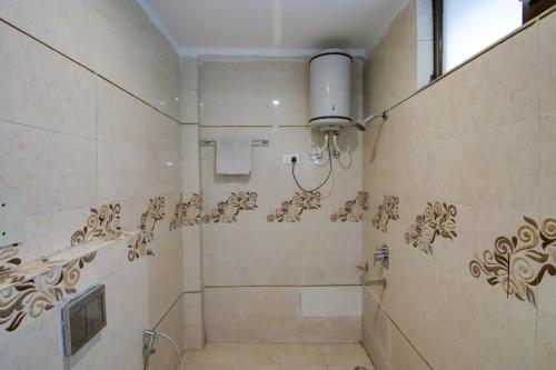 a bathroom with a shower with a tiled wall at Hotel Varuni- On Mall Road, Mcleod Ganj, Dharamshala in Dharamshala